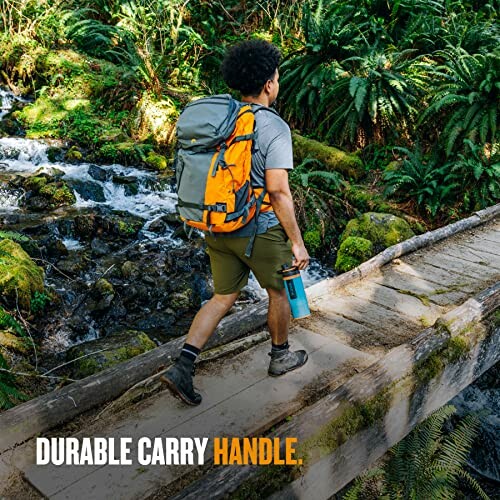 Hiker with backpack crossing a wooden bridge in forest